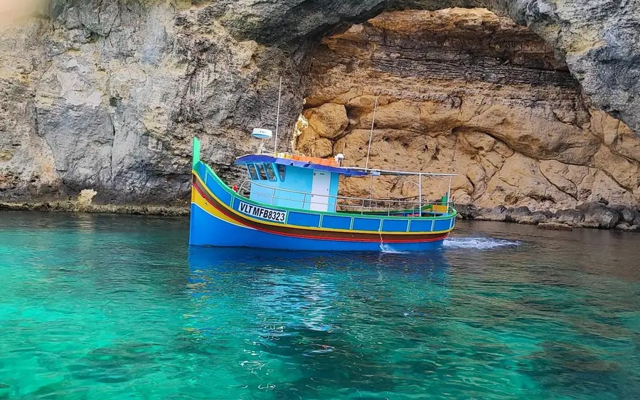 A traditional Maltese boat at a sea cave on Comino